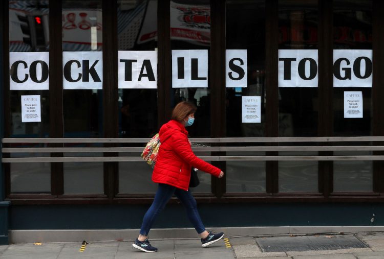 A woman walks past a pub in Dublin's city centre on Wednesday Oct. 21, 2020. With infections on the rise, the Irish government has imposed a tough new lockdown that begins at midnight Wednesday, shutting down non-essential shops, limiting restaurants to takeout service and ordering people to stay within five kilometers (three miles) of their homes for the next six weeks. (Brian Lawless/PA via AP)